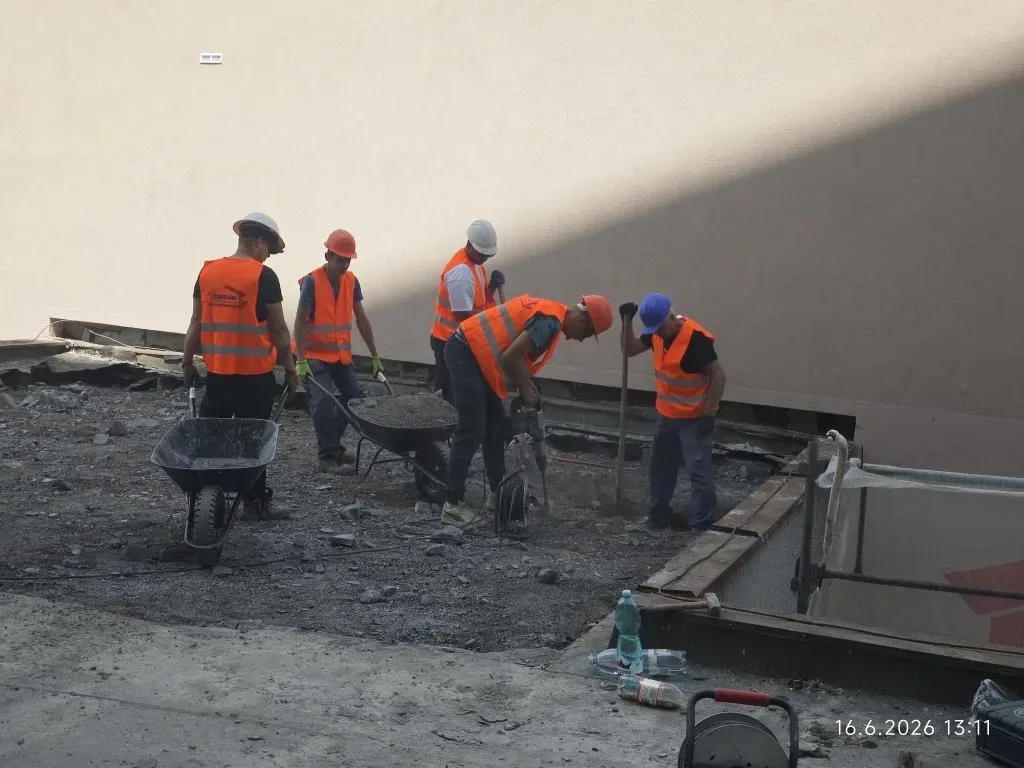 Pracovníci rozvážejí a ukládají beton při betonáži plochy